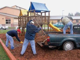 Volunteers from Agilent Technologies lay down new bark around the playground equipment of Apple Preschool on 135 S. French Ave. in Arlington.