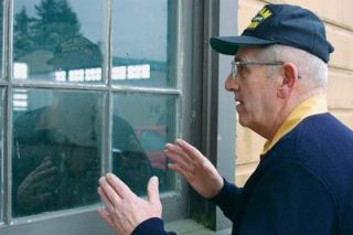 Richard Logg Sr. peers into the window of the old firehouse at the Arlington Airport recently. Logg is planning a ceremony to decommission the old building