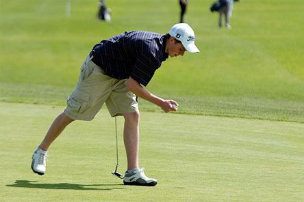 Jack Lindley reaches and grabs his ball after finishing the fifth hole.