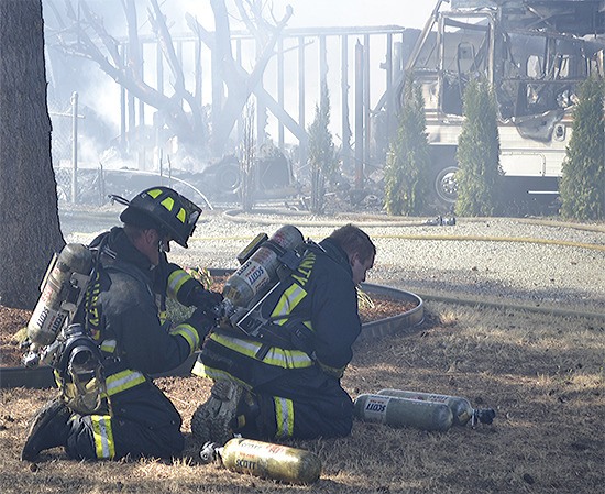 One firefighter helps another after fighting a fire just off Interstate 5 at Smokey Point. The blaze destroyed a home and nearby motor home.