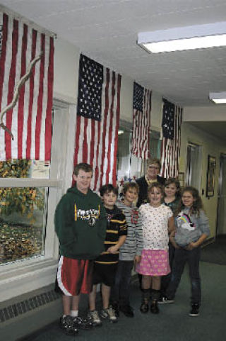 Kent Prairie Elementary School Principal Kathy Engell gathers a group of students to admire the flags displayed in the school hallway. Pictured are Connor Stephens