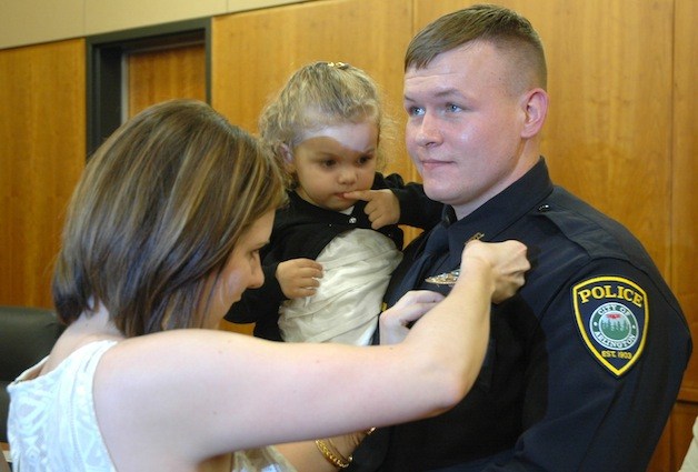 Arlington Police Officer Justin Olson's badge is pinned on by his wife