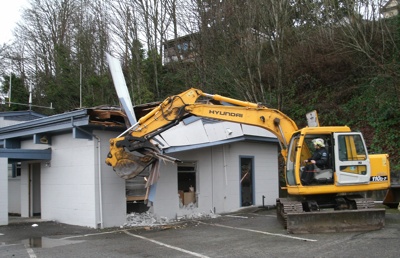 Arlington firefighters use a backhoe to knock down Station 46's remaining roof system