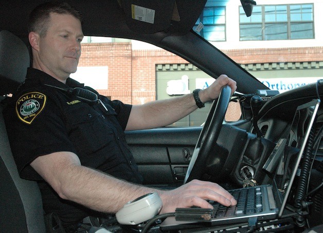 Arlington Police Officer Ken Thomas checks his files before heading out on patrol.