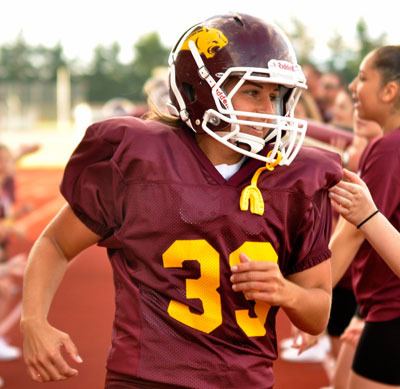 Lakewood Cougar Mama Sarah Schultz is cheered on by spectators and cheerleaders as she enters the field for the annual Powder Puff Football game at Quil Ceda Stadium on June 28.