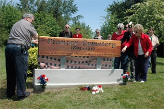 Mayor Margaret Larson helps unveil the sign that dedicates the town’s first cemetery to Harry Yost and Bill Senica