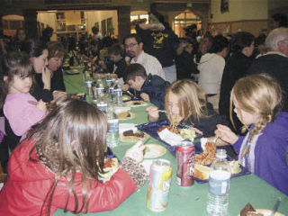 Hannah and Chloe Jensen slurp up spaghetti at a fundraising dinner to benefit the Mark Lee Family Fund. The family lost their house to a fire Nov. 21 which also took the lives of two boys