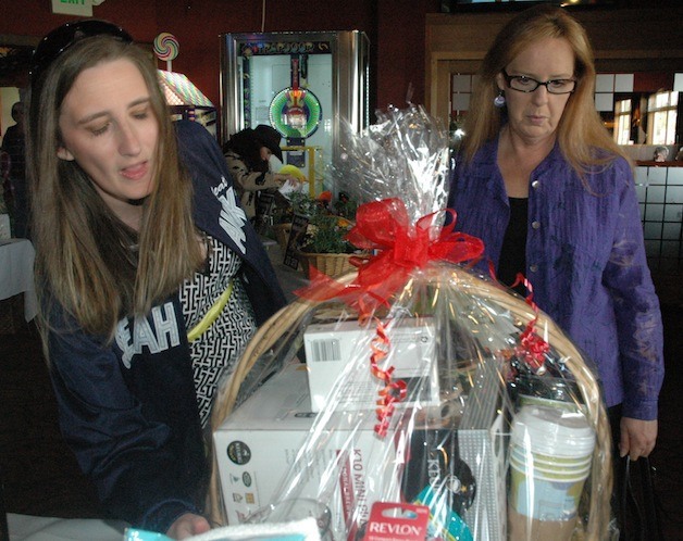 Tiffany Poynter and Theresa Laschober check out a Keurig Coffee gift basket during the Buzz Inn Steakhouse’s ‘Oso Strong’ silent auction on April 26.