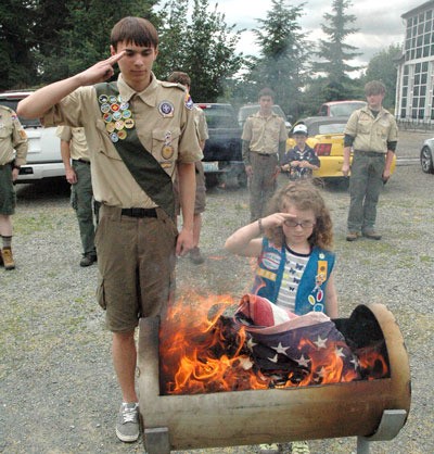 Local Boy Scout Donald Janda and Girl Scout Megan Munsee render salutes after retiring their flags during the June 14 Flag Day ceremony at the Stillaguamish Valley Pioneer Museum.