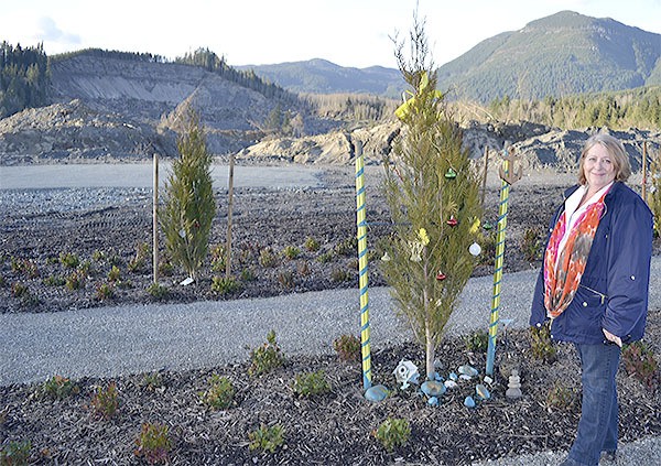 Arlington Mayor Barbara Tolbert stands by one of the trees planted in honor of the 43 victims of the Oso slide. A memorial will take place on the one-year anniversary Sunday.