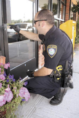 Arlington Police Officer Mike McQuoid dusts for fingerprints on the front door of The Arlington Times Aug. 23.