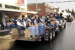 The Arlington High School football team rides in style in the AHS Homecoming Parade through a damp downtown Arlington evening Sept. 24.