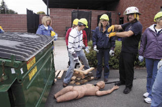 Darrington firefighter Denny Fenstermaker explains to Arlington School District employees how wooden planks and pry-bars can be used to lift heavy objects during search and rescue.