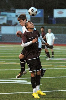 Josue Rivera controls possession with his head as an oncoming defender slams into him.