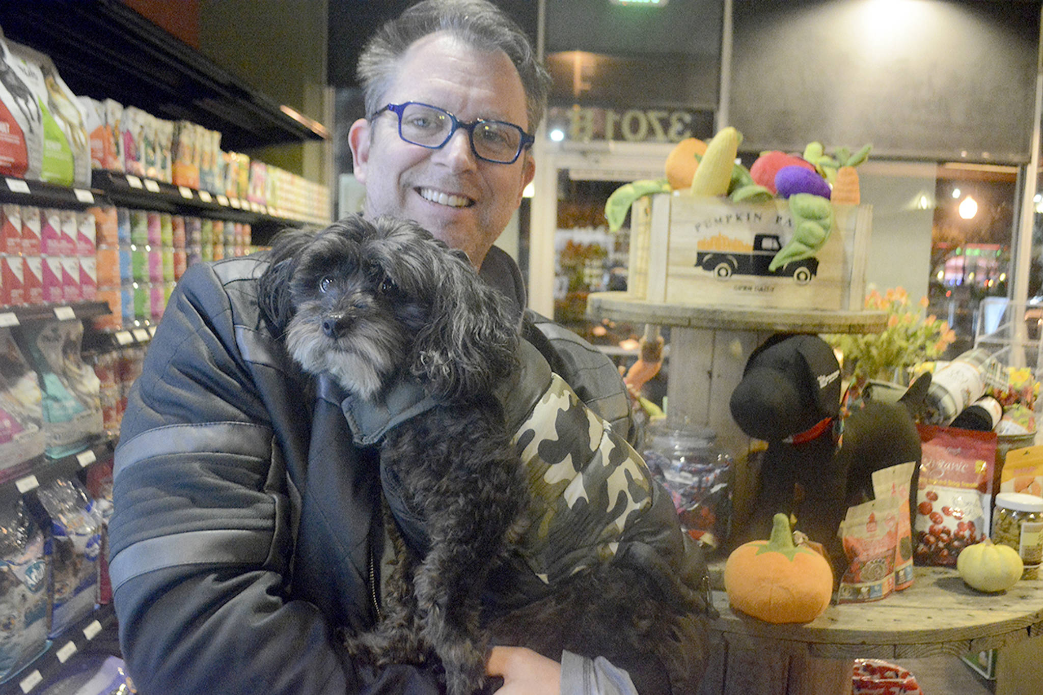 Dan holds one of their dogs, who is wearing their clothing apparel.